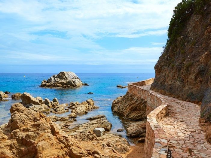 Steiniger Küstenweg des Camí de Ronda am türkisblauen Meer